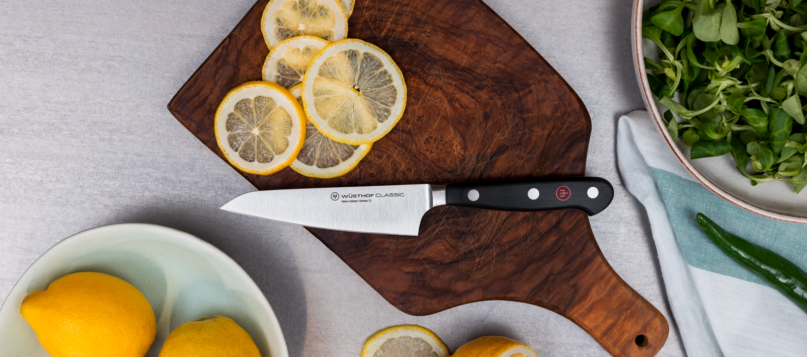 Wusthof knife on a cutting board with lemons.